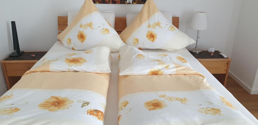 罗拉赫Ferienwohnung Dreiländereck 1的一间卧室配有两张床、白色床单和花卉枕头