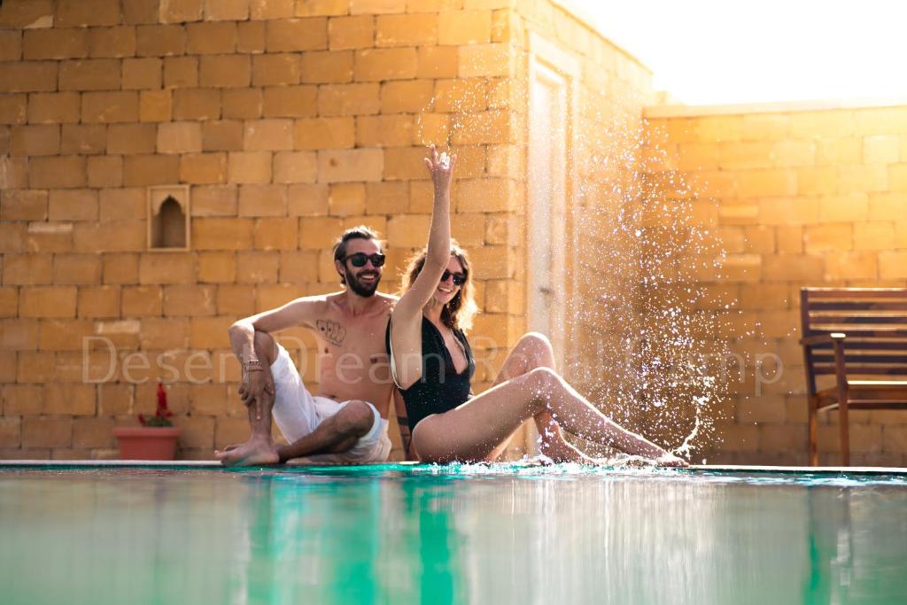 斋沙默尔Desert Dream Royal Camp with Pool的坐在游泳池边的男人和女人