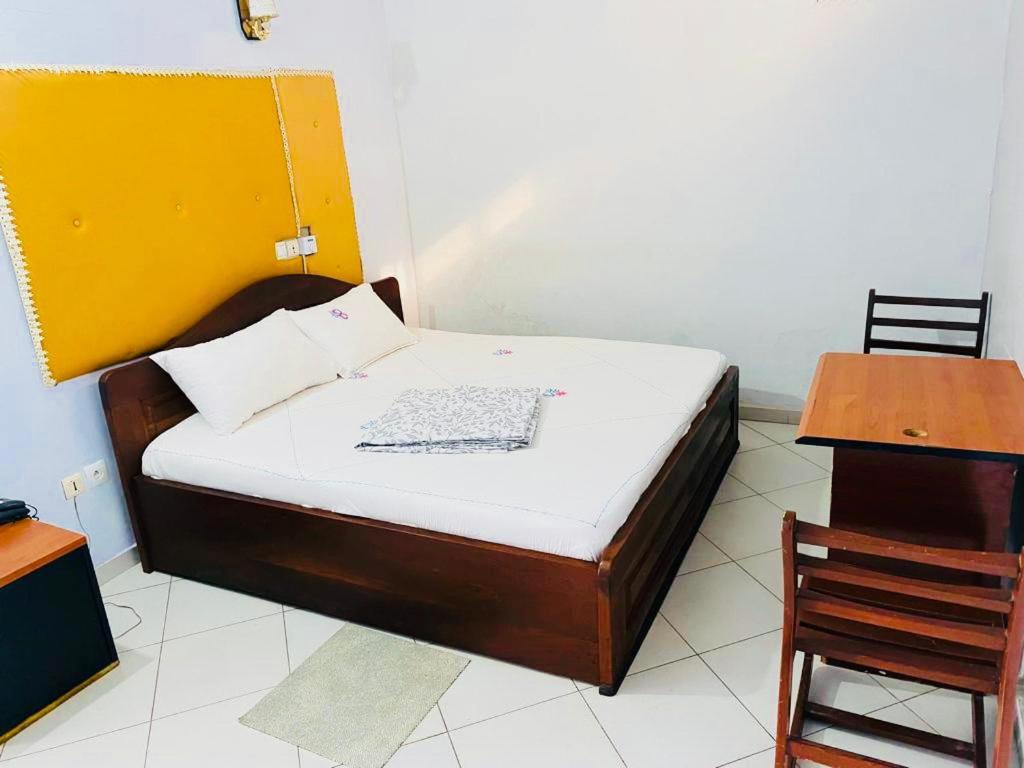 科托努AULNES RESIDENCE HOTEL的一张位于带桌子和椅子的房间内的床铺