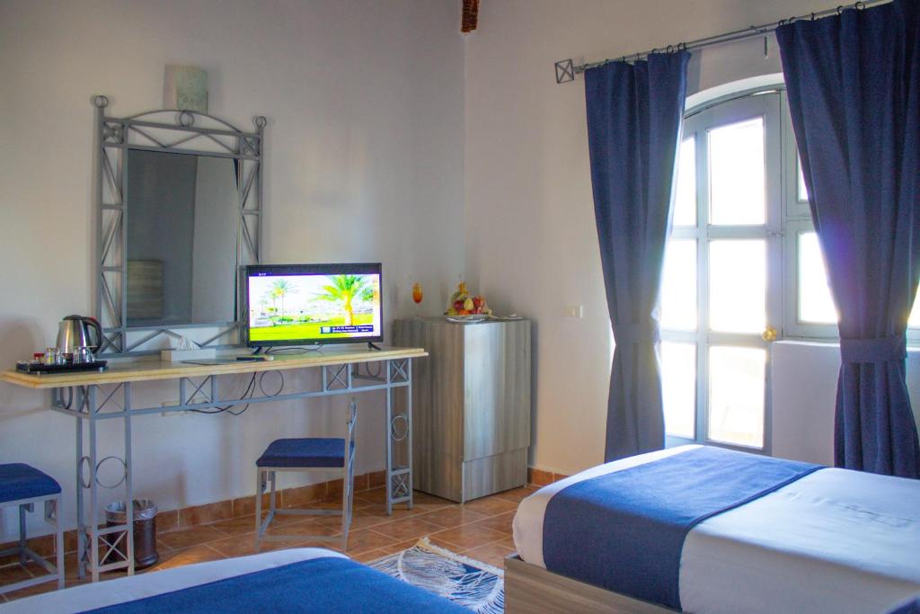 马萨阿拉姆Protels Beach Club & SPA的一间卧室配有两张床和一张书桌及电视