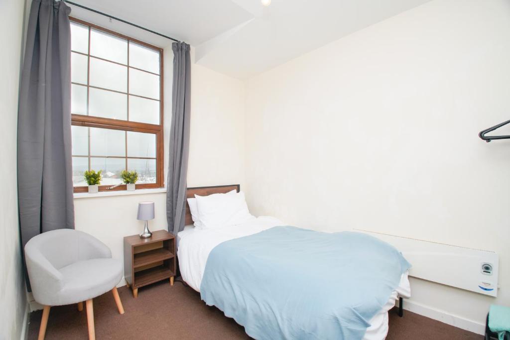 罗奇代尔3 bed apartment, centre of Rochdale的卧室配有床、椅子和窗户。