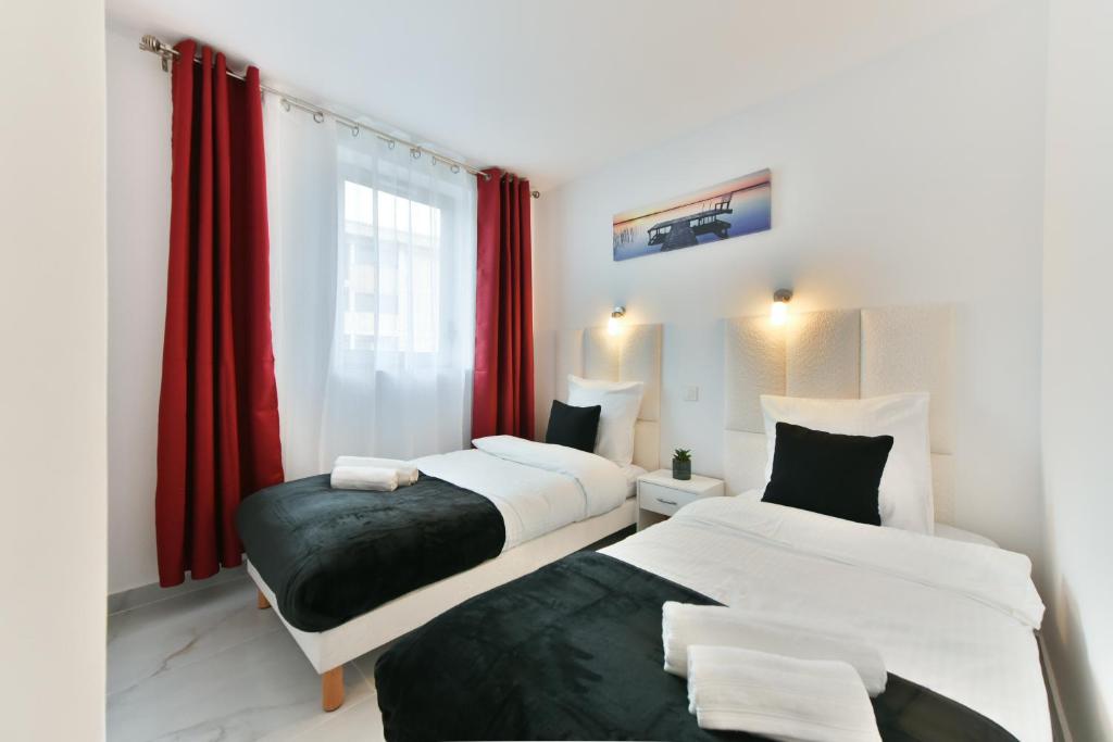 戛纳Stylish 2 rooms in the heart of Cannes的配有红色窗帘的客房内的两张床
