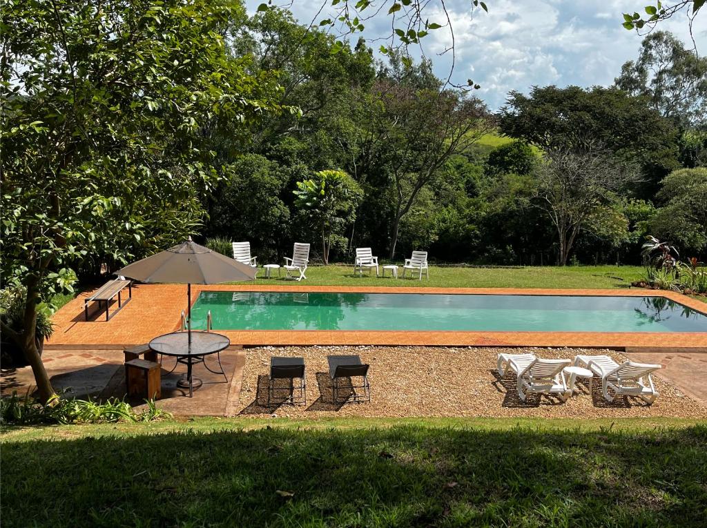 布罗塔斯Hospedaria do Feno的一个带椅子和桌子的游泳池以及一把遮阳伞