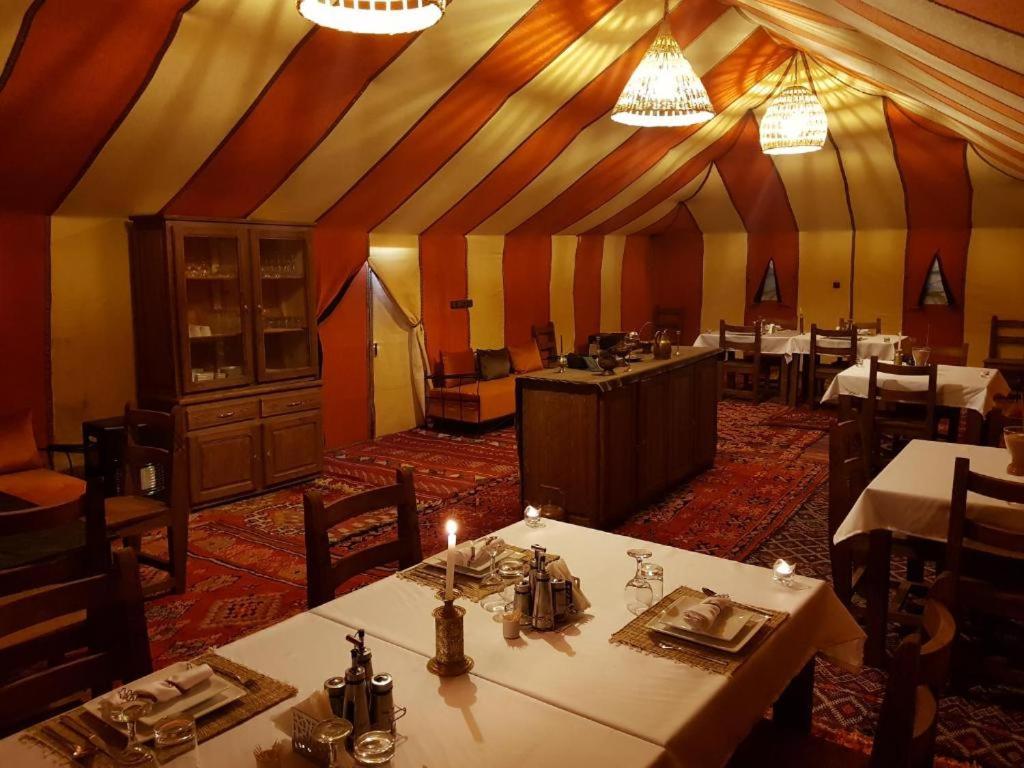梅尔祖卡Sahara Safari Camp的餐厅内带桌椅的用餐室