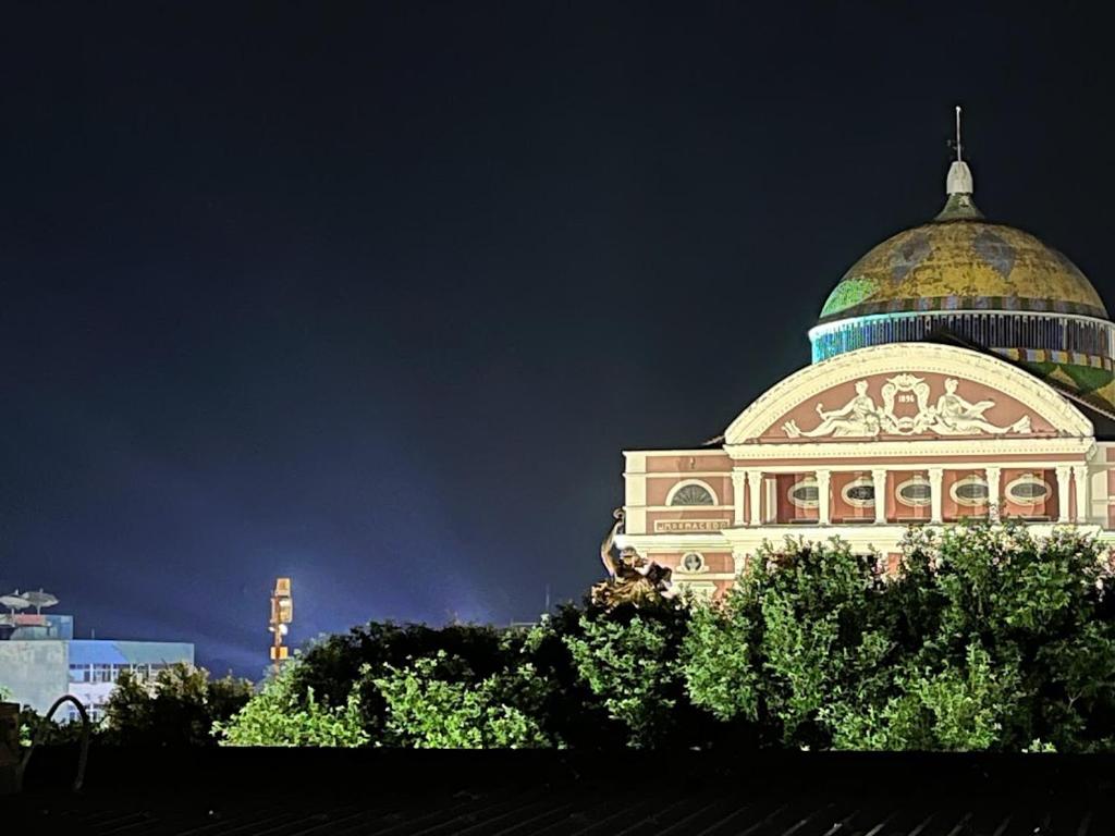 马瑙斯Hospedagem Residencial de Frente ao Teatro Amazonas的一座在晚上顶部有圆顶的建筑