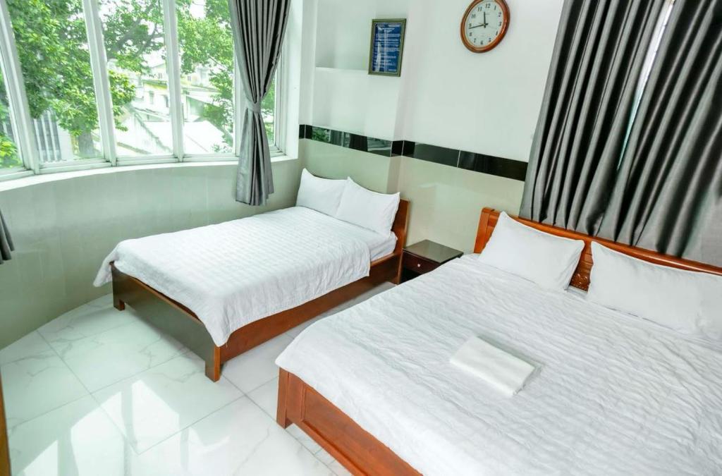 胡志明市THANH NGỌC HOTEL的一间设有两张床的客房和墙上的时钟