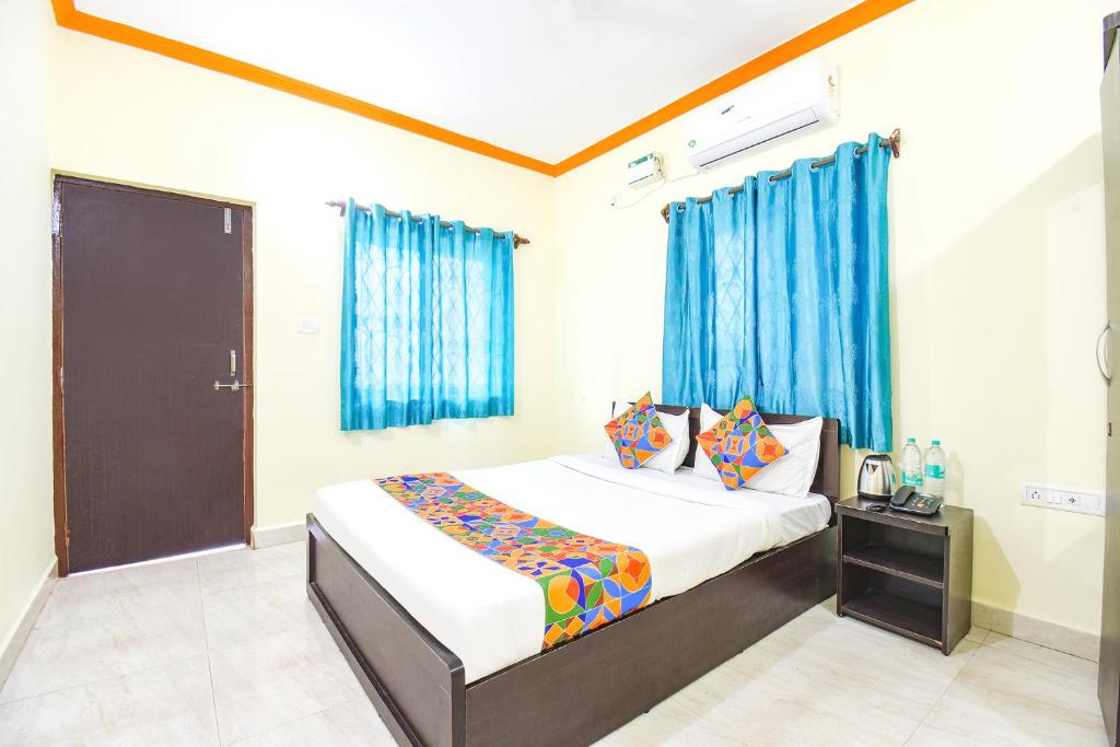 巴加FabExpress Shanel Beachside Resort的一间卧室配有蓝色窗帘的床