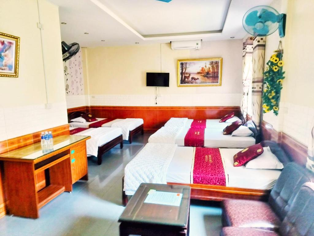Xuân ÐàiGRAD Hoa Do Hotel的酒店客房设有三张床和一张书桌