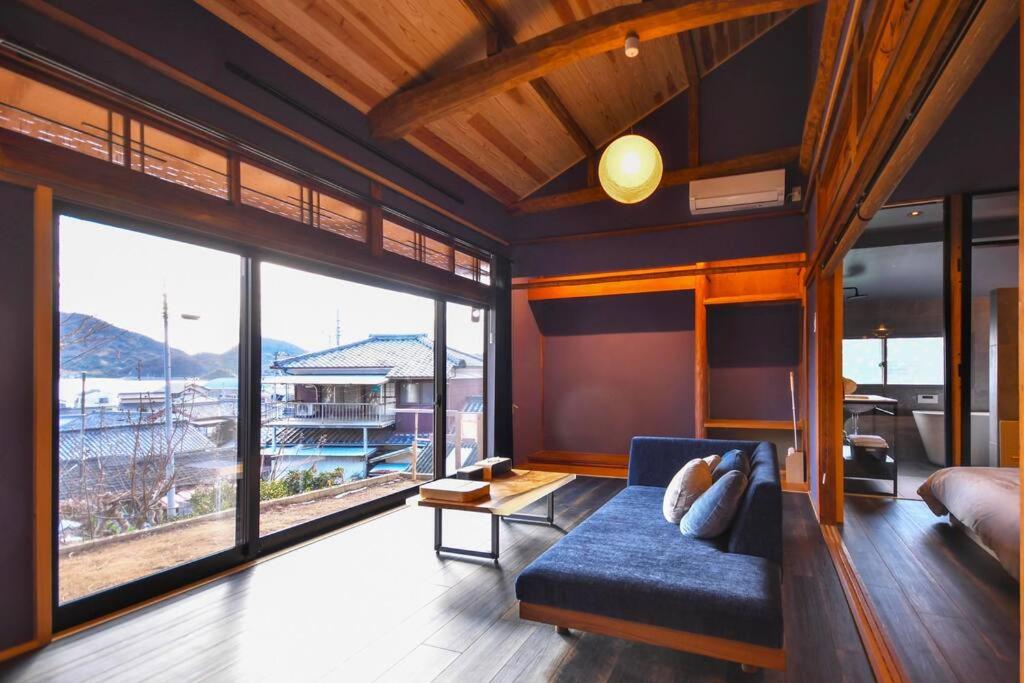 松山由良民泊島宿的客厅设有蓝色的沙发和大窗户