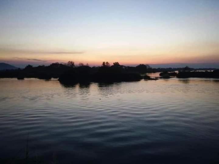 Muang KhôngSunset bungalows的一大片水,背景是日落