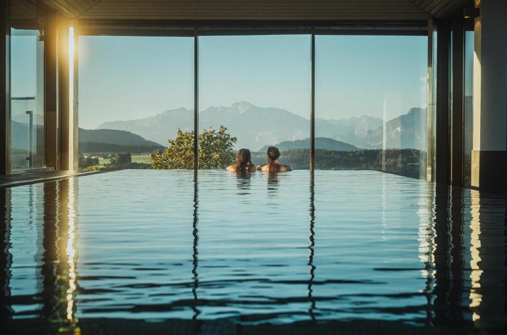 伊利豪森Romantik Spa Hotel Elixhauser Wirt的两名儿童在山地游泳池游泳