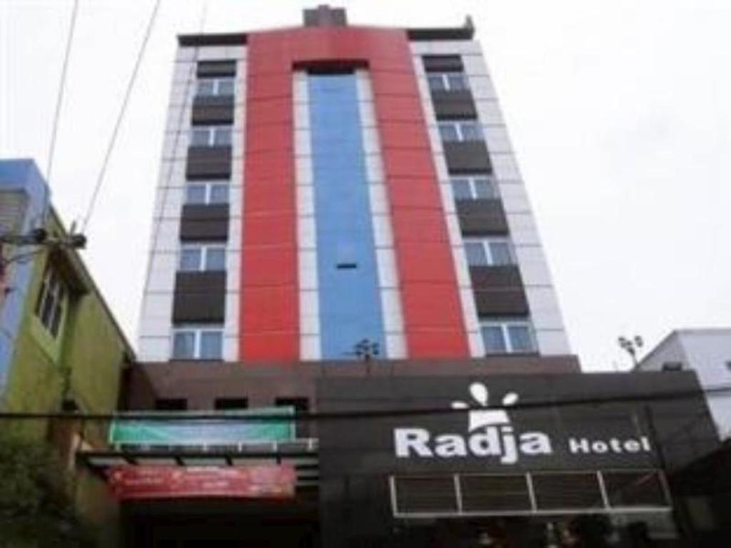 沙马林达Radja Hotel的一座高大的红色和白色建筑,有商店