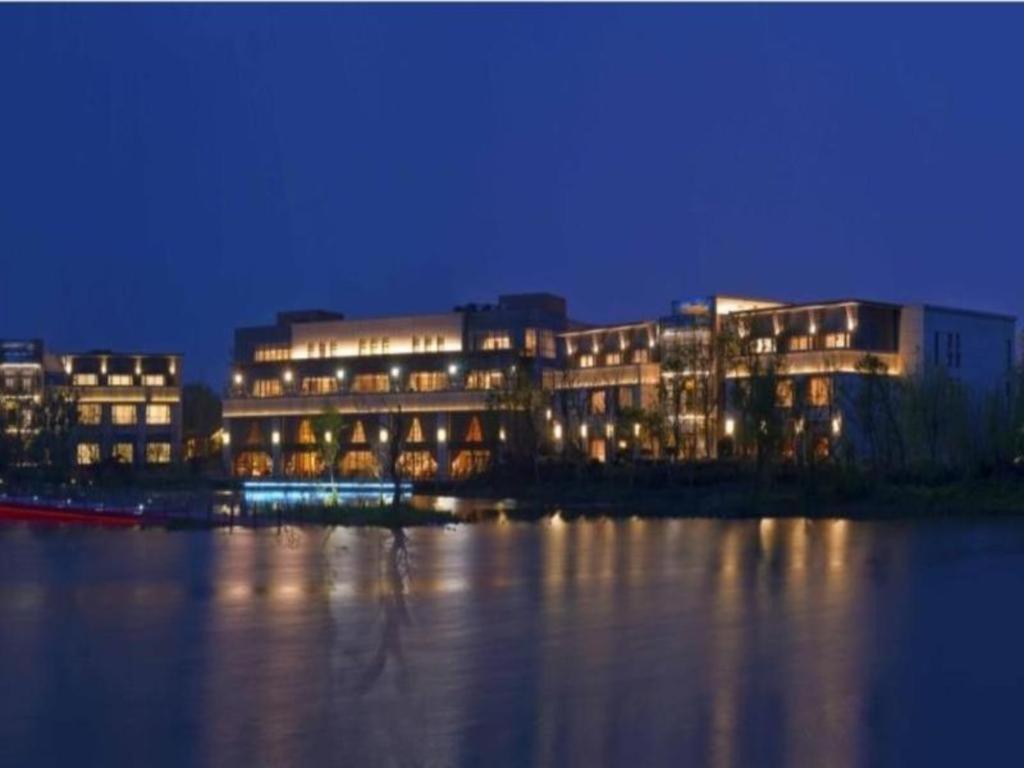 BeigangChangzhou Fudu Qingfeng Garden Hotel的夜间水边的一座灯火通明的建筑