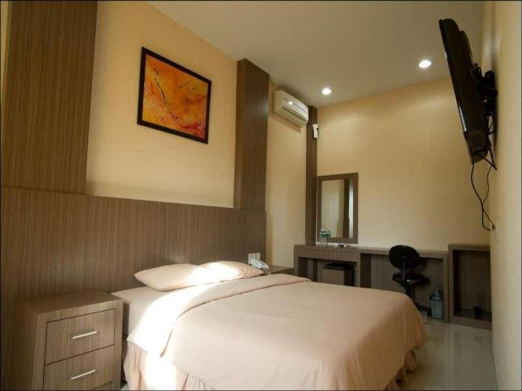 ParitBenteng Hotel Pekanbaru的卧室配有一张床,墙上配有电视
