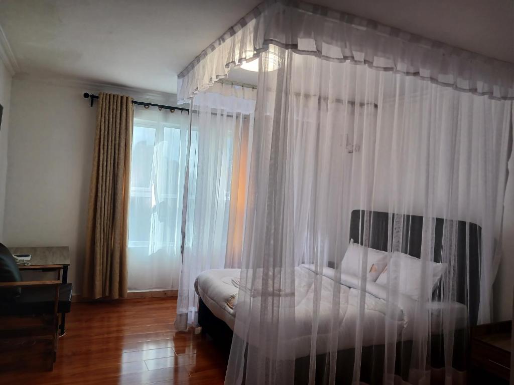 内罗毕TAWALA GARDEN HOTEL的卧室配有带白色窗帘的天蓬床