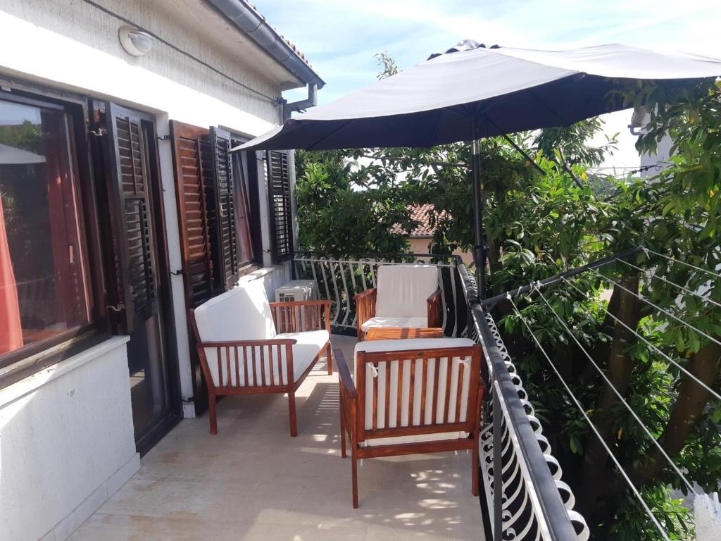 普拉Apartment Marija的庭院配有两把椅子和一把遮阳伞