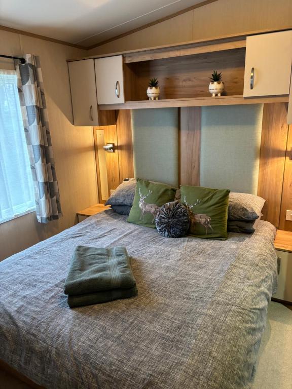 卡莱尔Woodpecker lodge, Camelot Holiday Park, CA6 5SZ的一间卧室配有一张带绿色枕头的大床