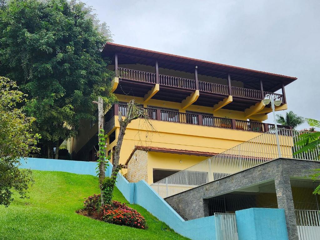 伊泰帕瓦Casa Feliz no Jardim Itaipava, 7 quartos, conforto的黄色的建筑,旁边设有阳台