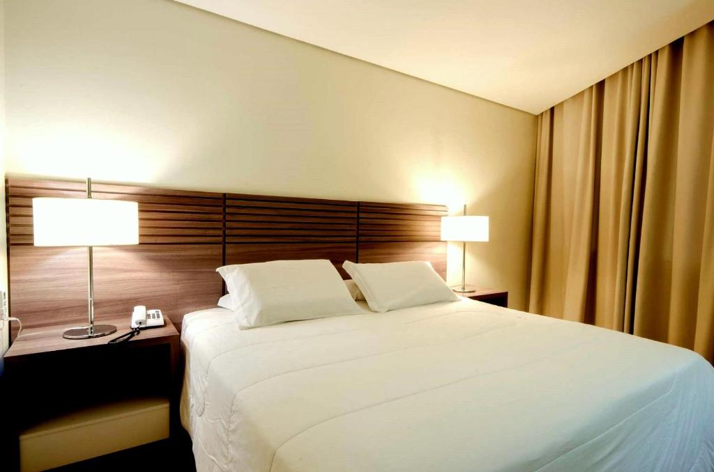 阿雷格里港Umbu Hotel Porto Alegre - Centro Histórico - Prox Aeroporto 15min的卧室配有一张白色大床和两盏灯。