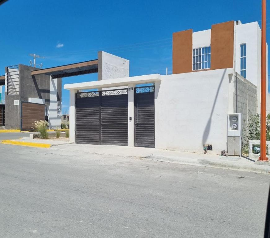 Ciudad AcuñaCasa Amistad的白色的建筑,在街上有两扇车库门