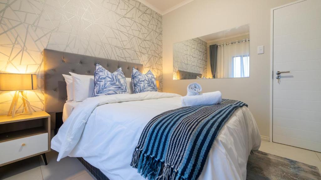米德兰Chic Modern Midrand Escape的卧室配有带蓝色枕头的大型白色床