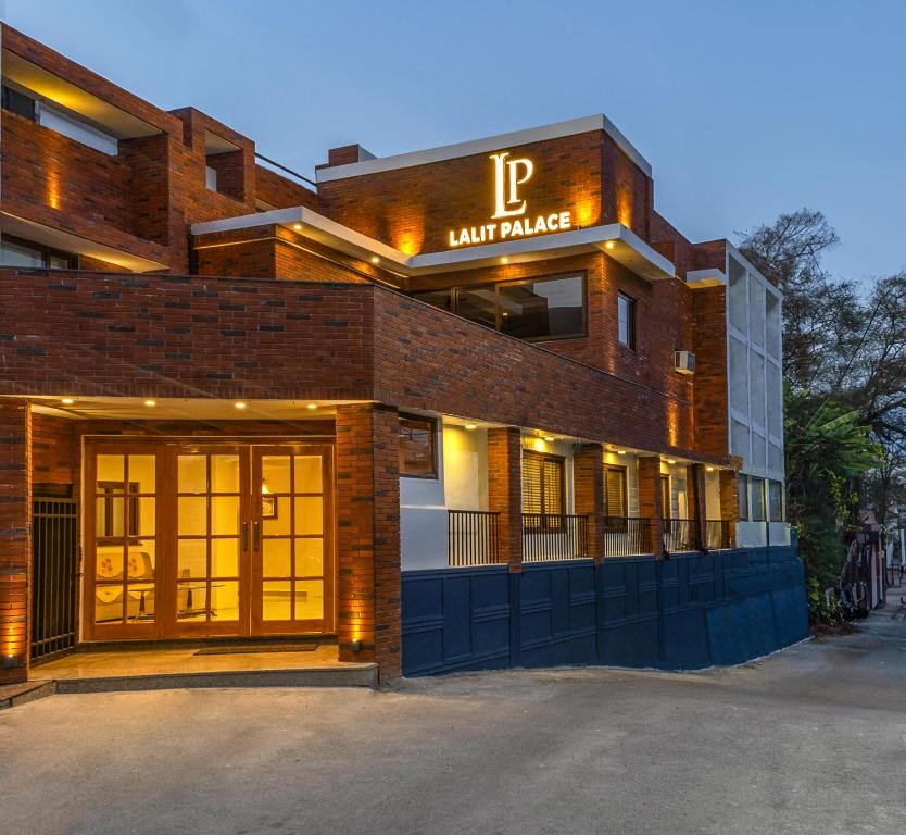 德拉敦Hotel Lalit Palace的砖砌的建筑,前面设有停车场