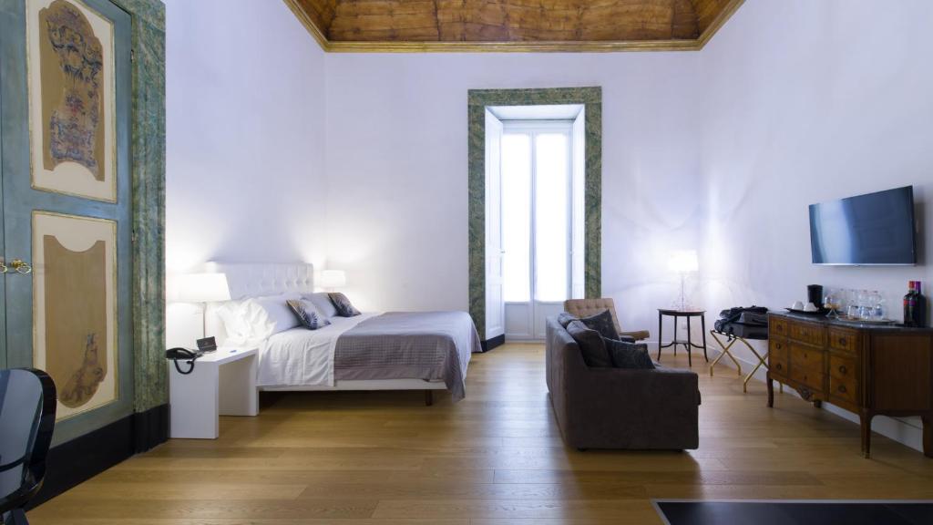 那不勒斯桑塔基娅拉精品酒店的一间卧室配有一张床、一张沙发和一台电视。