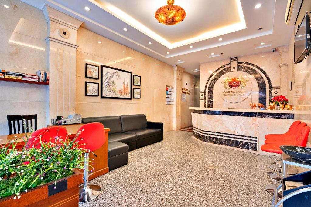 胡志明市HANZ The Beautiful Hotel Bui Vien Walking Street的一间设有黑色沙发和红色椅子的等候室