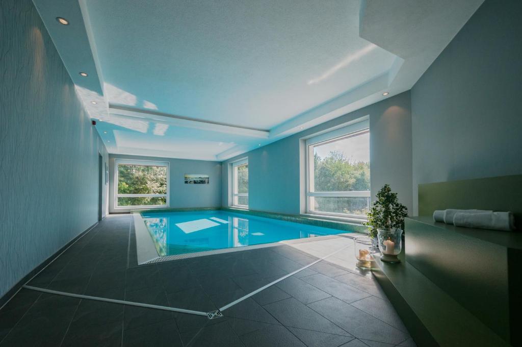 罗伊特林根Hotel Fortuna Reutlingen-Tübingen的大型客房设有带蓝色墙壁的游泳池