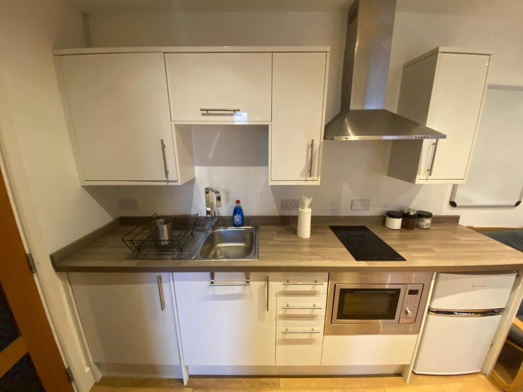 BansteadStudio apartment near Sutton, Croydon的小厨房配有白色橱柜和水槽