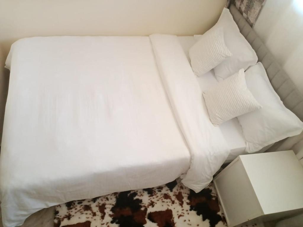 内罗毕The Pearl Cage Gigiri-Near US Embassy的一张带白色床单和枕头的床