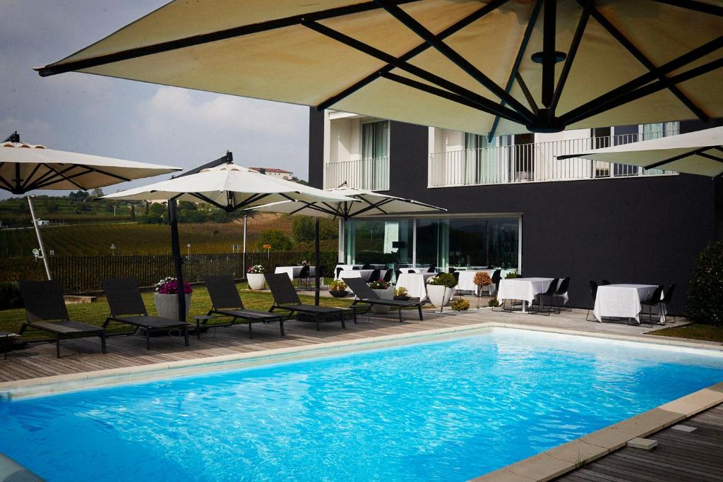 多博沃伊亚琴旅馆的一座带椅子和遮阳伞的游泳池位于一座建筑旁边