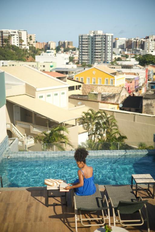 萨尔瓦多Canto Hotel的坐在游泳池旁椅子上的女人