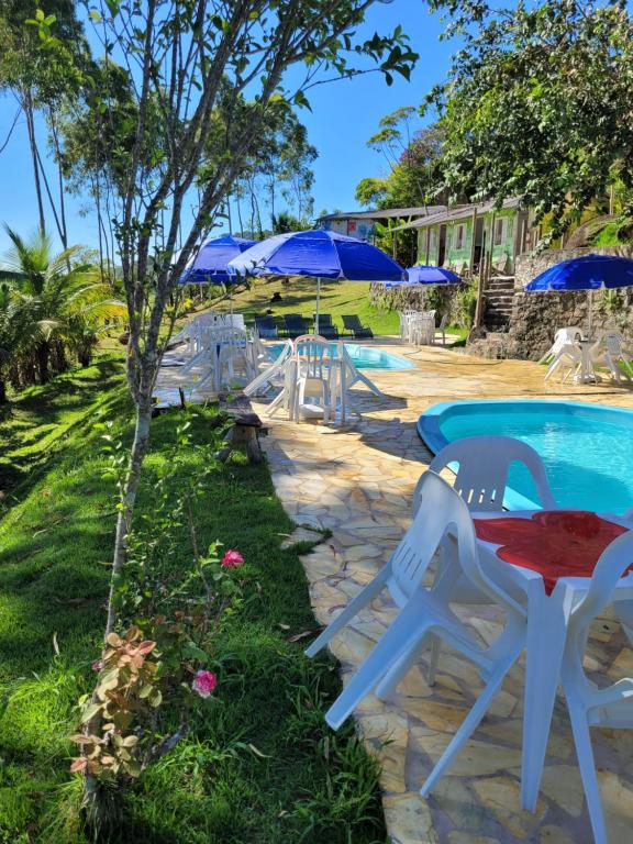乌巴图巴Refugio de Itamambuca的游泳池旁的桌椅,带遮阳伞