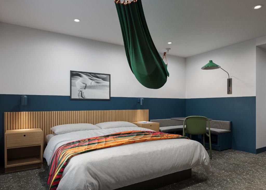 米苏拉LOGE Missoula的一间卧室配有一张床、一张书桌和一个绿色的吊灯。