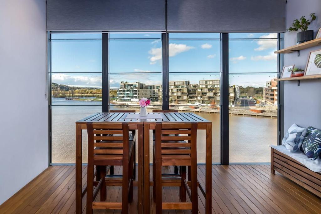 金斯顿Stunning 1BR Apartment with Water Views的餐桌、椅子和大窗户