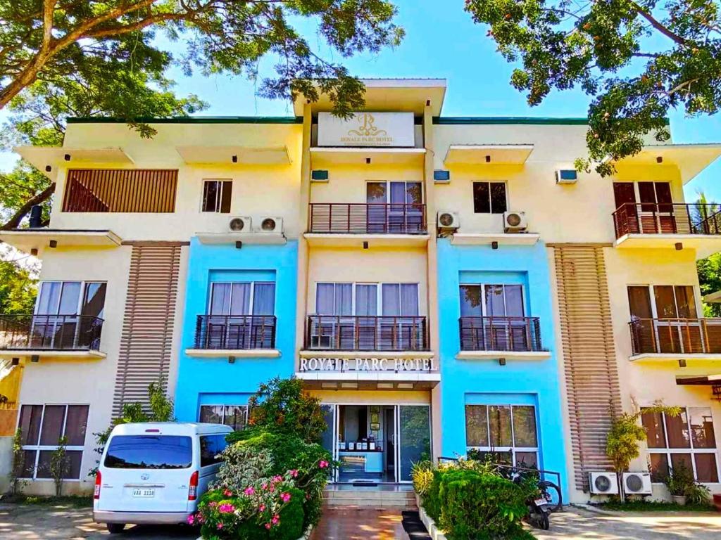 公主港Royale Parc Hotel Puerto Princesa Palawan的一座蓝色和白色的建筑,前面有停车位