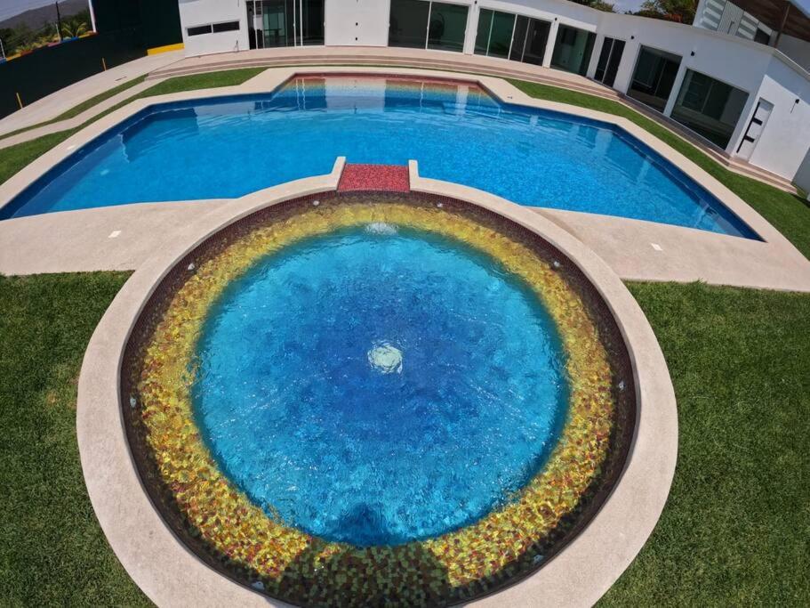 TicumánCasa de Lujo/10 minutos Estacas/ Cancha Frontón的享有一个蓝色大泳池的顶部景色,周围种有鲜花