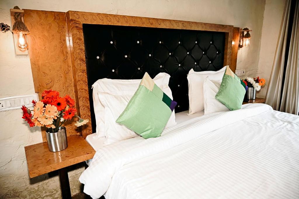 兰纳加Corbett Tiger Retreat的一张配有白色床单和绿色枕头的大床