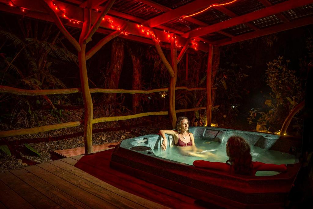 沃尔卡诺Volcano Inn Bed n Breakfast的两名妇女坐在森林的按摩浴缸里