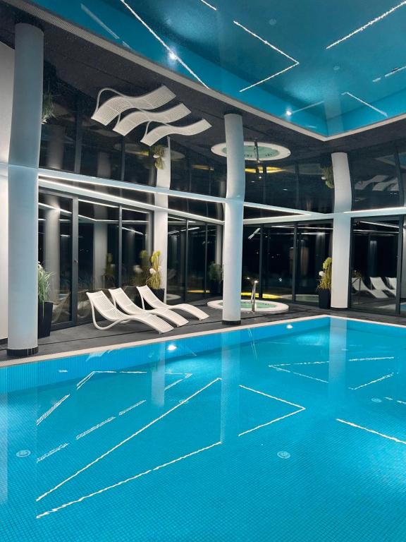 科沃布热格Westin House Resort Kołobrzeg Apartament DELUX的一座带白色椅子的建筑中的游泳池