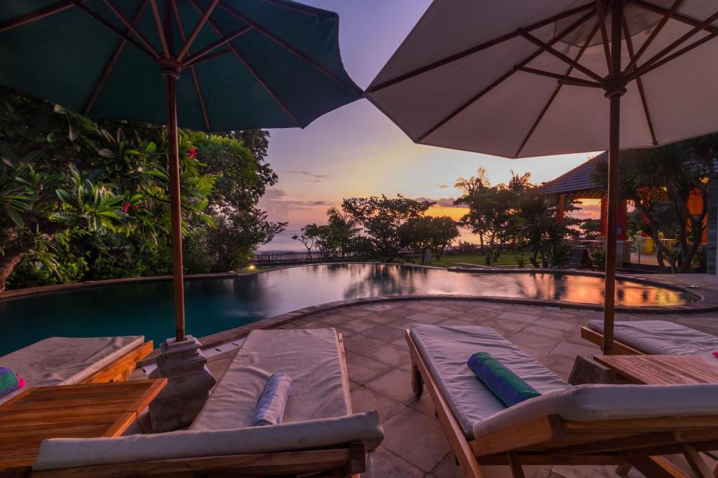 艾湄湾别墅天空舞者 - 巴厘岛酒店的游泳池旁的游泳池配有遮阳伞和躺椅
