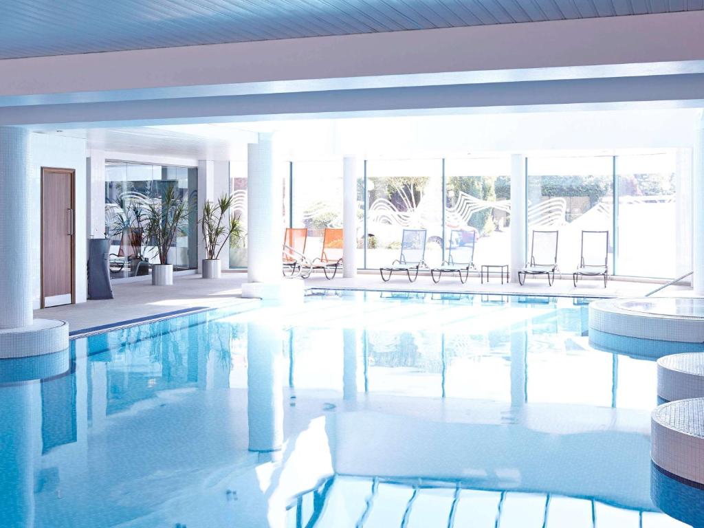 卡迪夫诺富特加的夫中心酒店的大楼内带椅子的大型游泳池