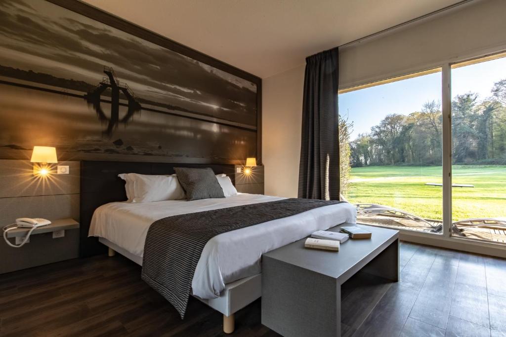 勒特隆歇圣马洛高尔夫度假酒店的一间卧室设有一张大床和一个大窗户