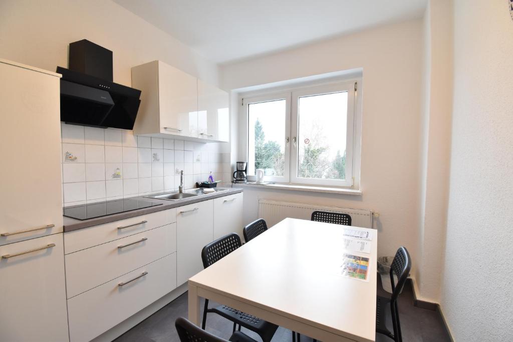 波鸿CoreRooms - Apartment Bochum Wattenscheid的厨房配有白色橱柜和桌椅