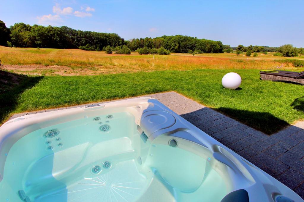 格赫伦-莱宾Luxus_EG_Fewo TEE ONE的草原上带高尔夫球的按摩浴缸