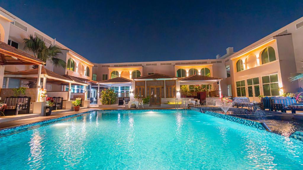 拉斯阿尔卡麦人达累斯萨拉姆公寓式酒店的一座游泳池,在晚上在建筑物前