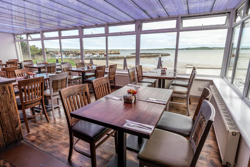 Bowmore路荷喜德酒店的一间带桌椅的餐厅,享有海滩美景