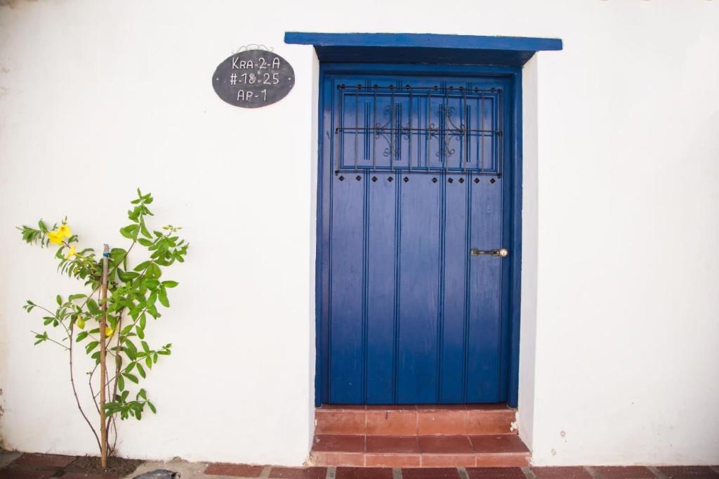 蒙波斯Apartamento Familiar Puerta Azul的白色墙壁上的蓝色门,有植物