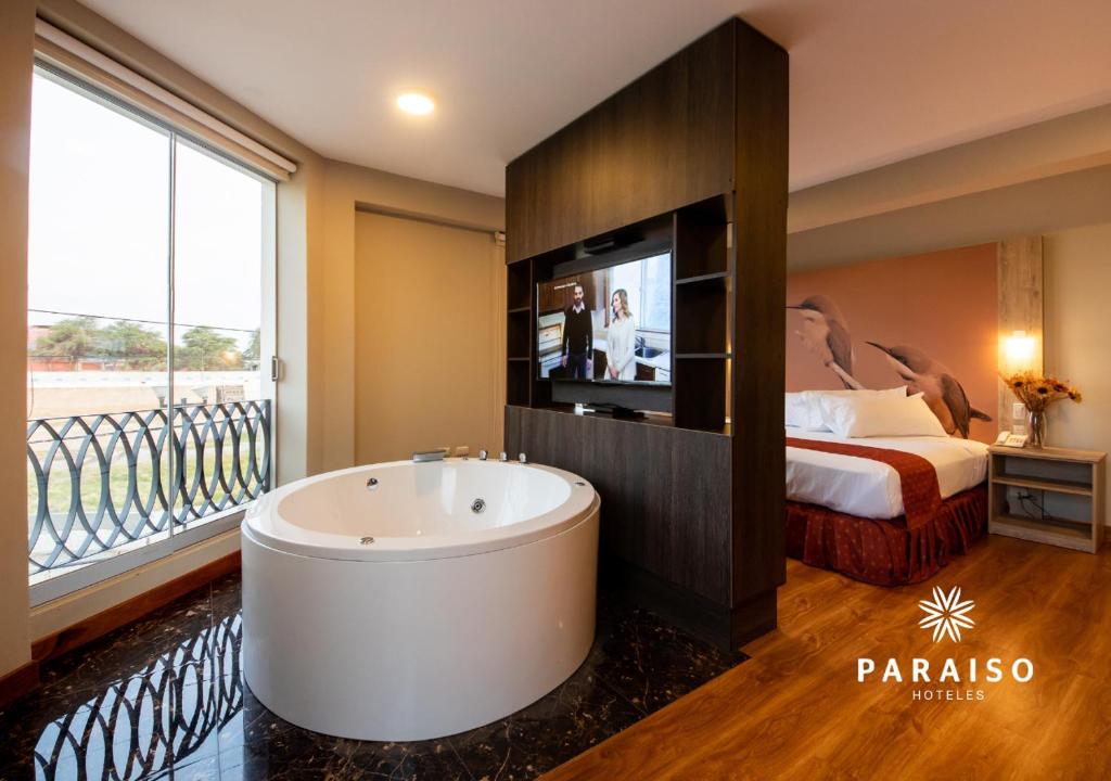 皮乌拉Hoteles Paraiso PIURA的带浴缸、床和电视的浴室